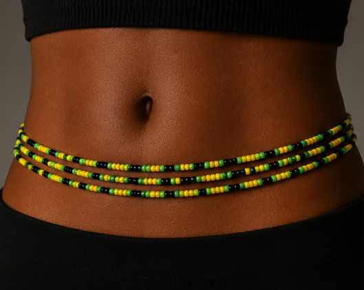 A close-up of a person's waist wearing a beaded waist wrap or belt made of small black, yellow, and green beads. Jamaica waist beads by waist beauty