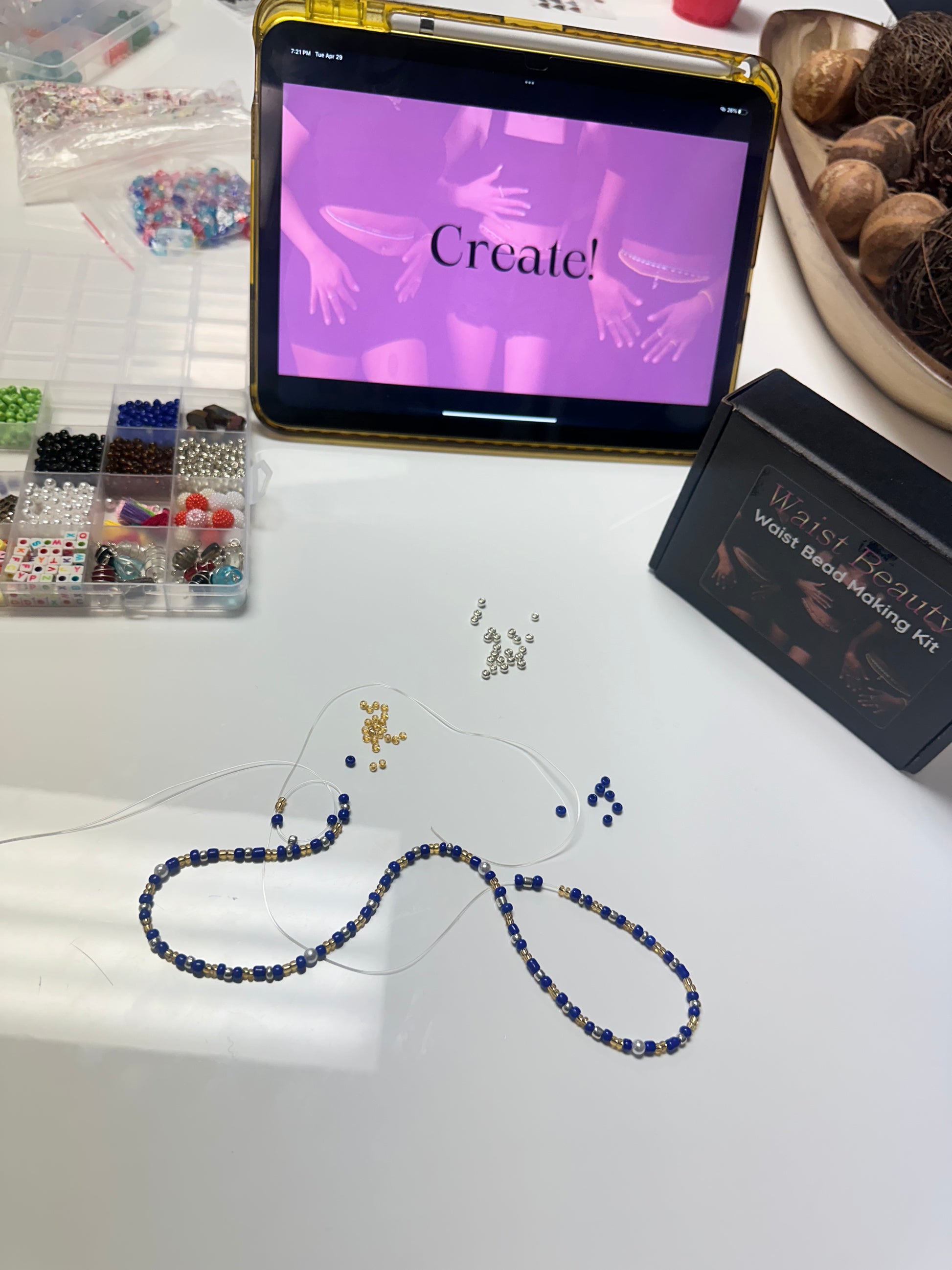 Beaded necklace on a table with a tablet displaying 'Create!' and a Winstead wax modelling kit.