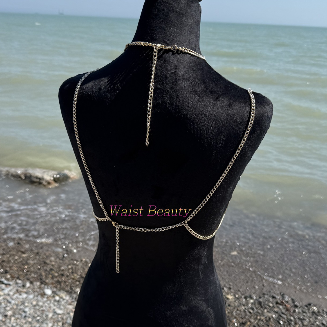 Waist Beauty - Translucent blue, orange, and clear crystal beaded body chain bra with gold fringe accents on a black mannequin at the beach.