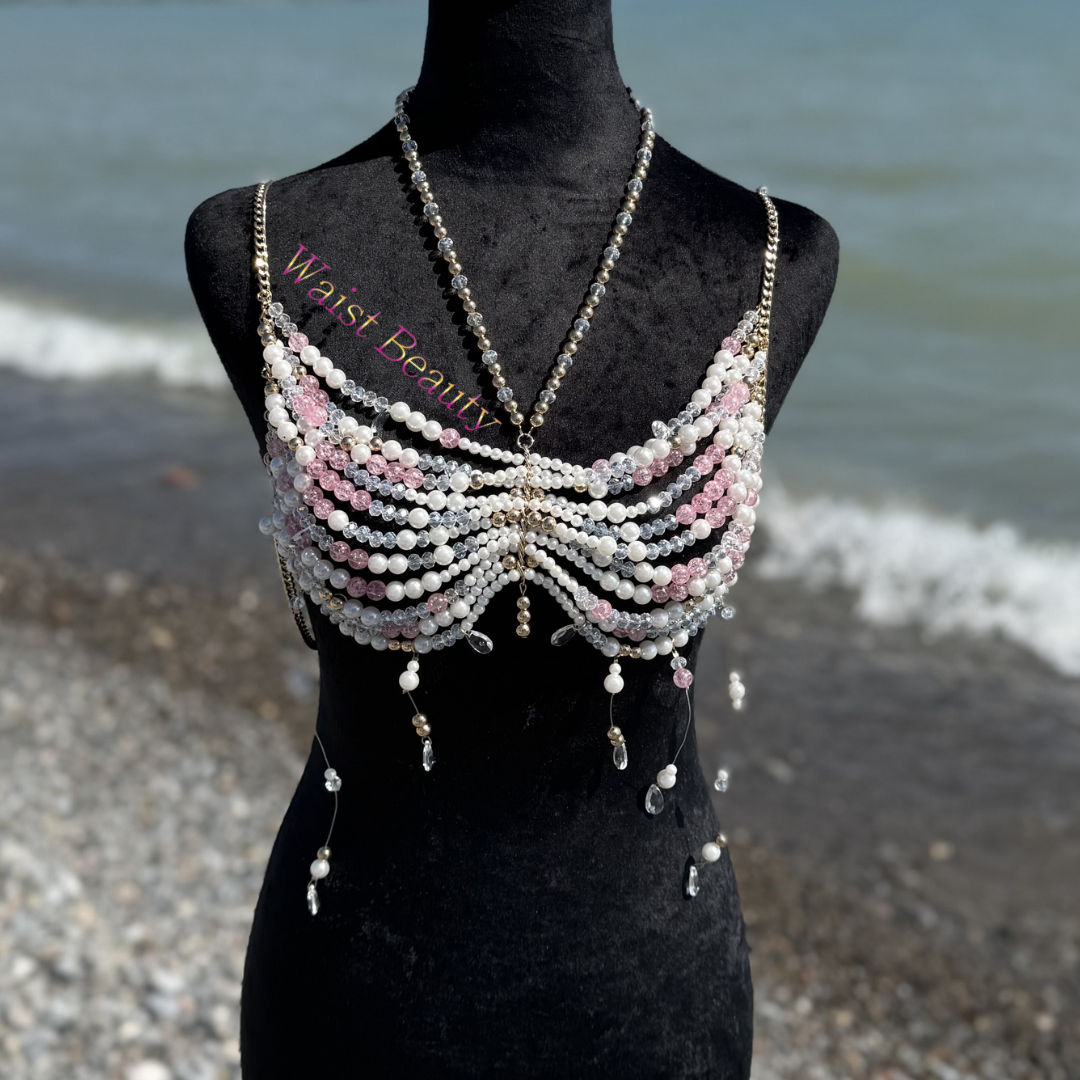 White and blush pink pearl butterfly-shaped beaded body bra with gold chain accents on a mannequin.