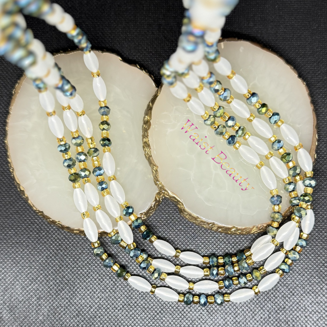 Immerse yourself in oceanic luxury with the Coastal Dream tie-on waist beads. This stunning design combines smooth, luminous opalescent white rice beads with a wave of shimmering metallic teal and blue-green bicone crystals. Finished with warm gold spacer beads, this 53-inch strand brings an immediate sense of harmony, loyalty, and deep
