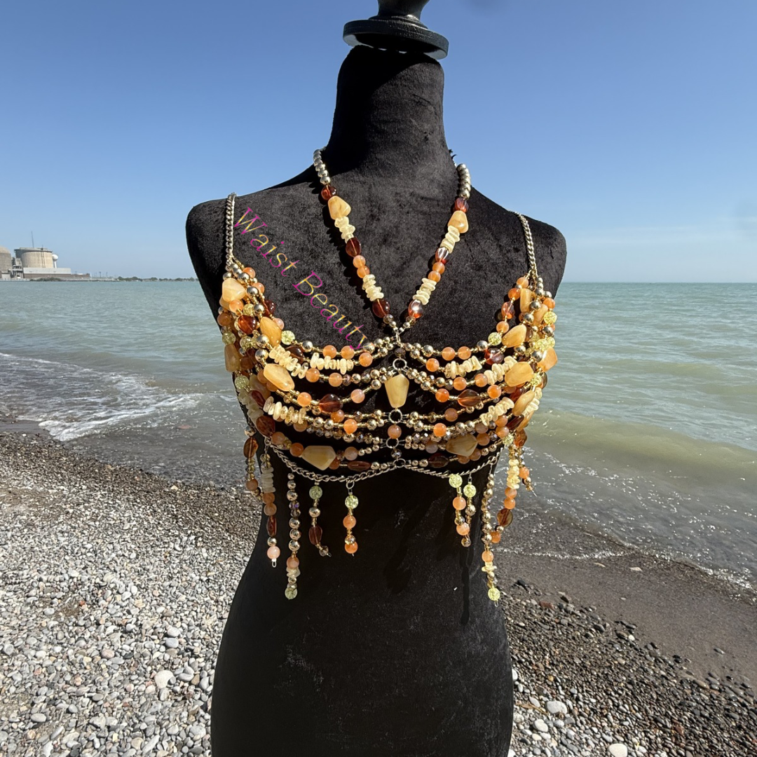 Golden hour goddess top featuring bohemian gold chains and amber stone beads on a black mannequin by the ocean.
