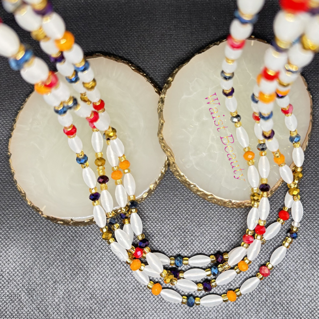 “Tie-on waist bead strand featuring opalescent rice-shaped beads, multicoloured crystal rondelles, and metallic gold seed beads. The 53-inch design reflects rainbow-like light and layers easily for a vibrant, radiant look.”